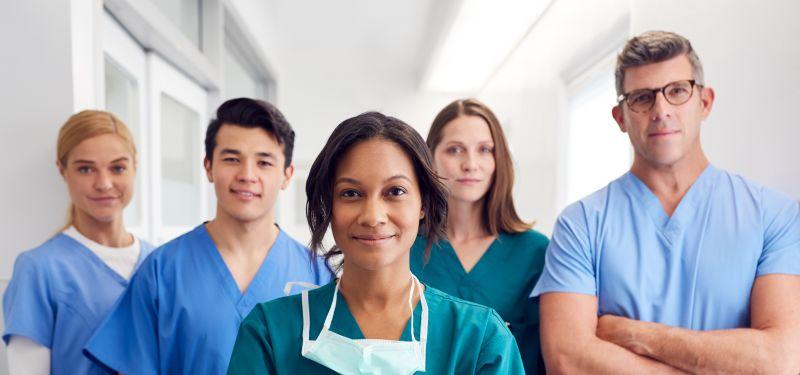 Five nurses standing next to each other smiling